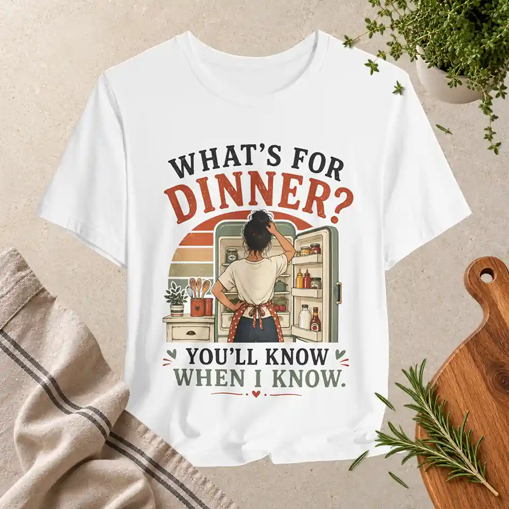 White T-shirt with retro illustration of a woman looking inside a refrigerator and the quote “What’s for Dinner? You’ll Know When I Know.”